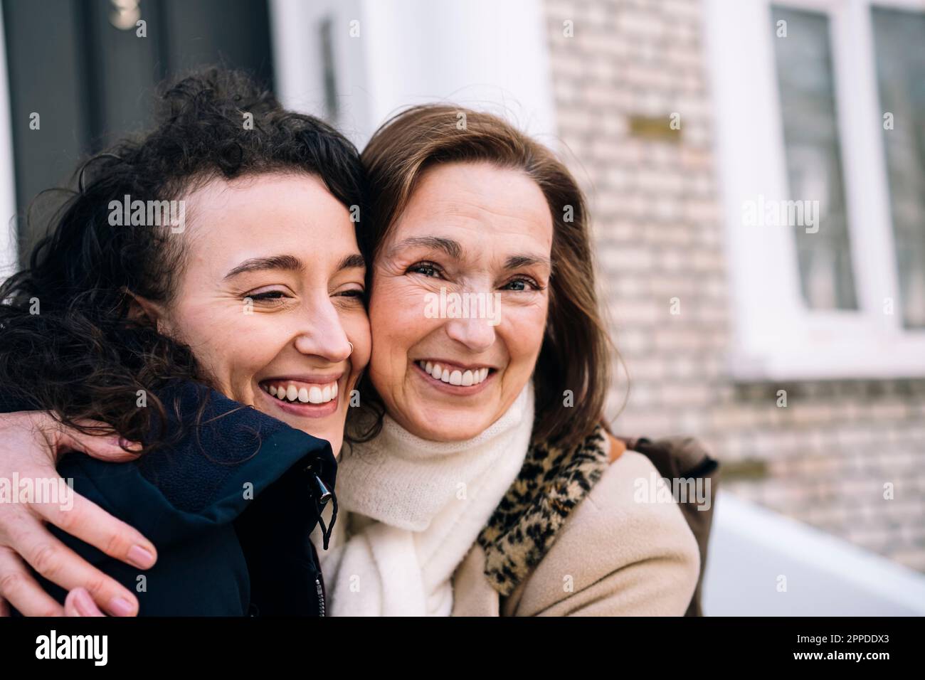 Fröhliche Tante umarmt Nichte vor dem Gebäude Stockfoto