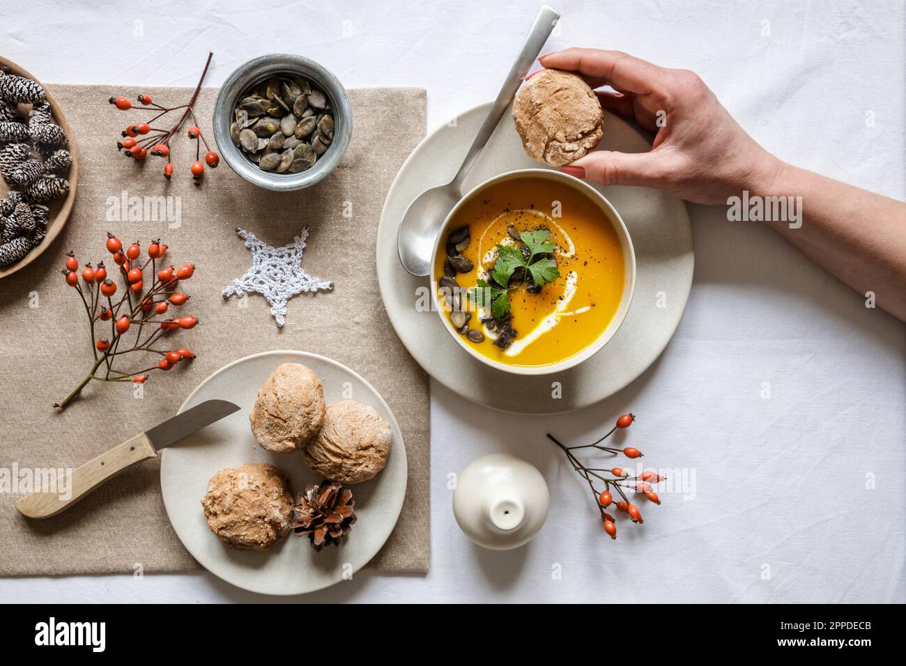 Eine Frau isst eine Schüssel Kürbissuppe mit hausgemachten Brötchen Stockfoto