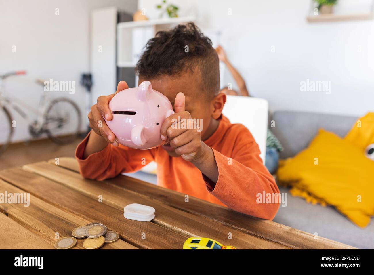 Ein Junge, der zu Hause ein Sparschwein eröffnet, um Münzen zu zählen Stockfoto