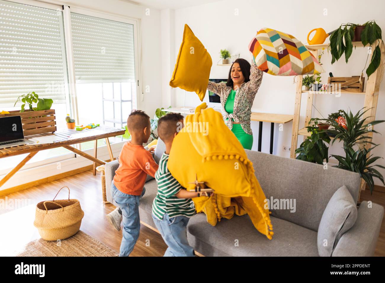 Verspielte Mutter spielt Kissenschlacht mit Zwillingssöhnen zu Hause Stockfoto