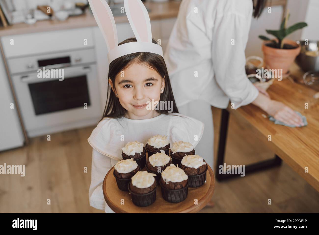 Lächelndes Mädchen mit Cupcakes am Ostertag zu Hause Stockfoto
