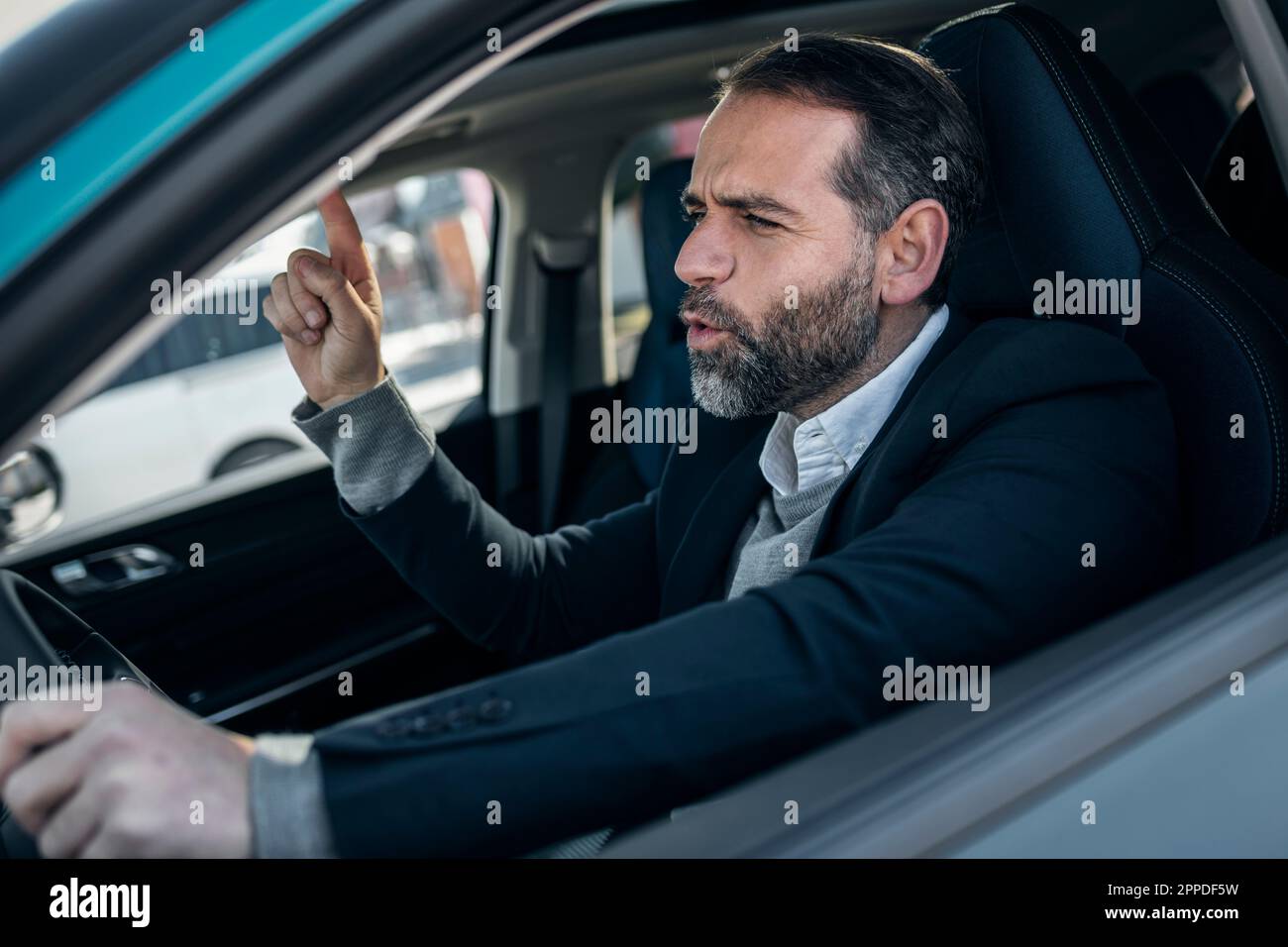 Ein fröhlicher Geschäftsmann, der im Elektroauto Musik hört Stockfoto