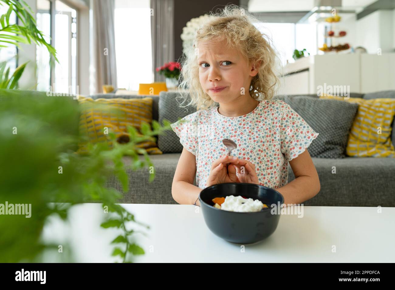 Blondes Mädchen weigert sich, zu Hause in der Schüssel zu essen Stockfoto