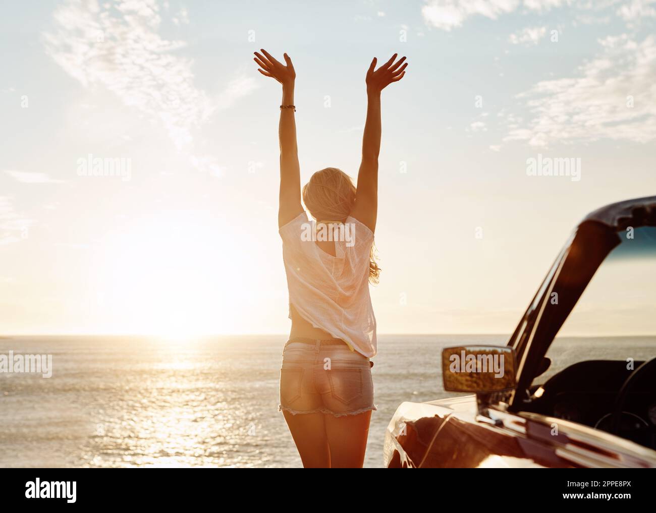 Sag Hallo zu den Sommerabenteuern. Eine glückliche junge Frau, die einen Roadtrip im Sommer genießt. Stockfoto