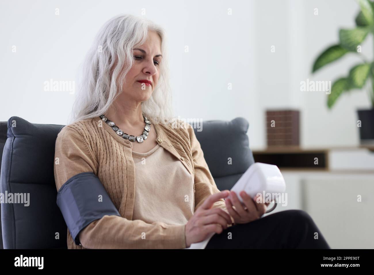 Alte Frau verwendet ein digitales Tonometer zur Blutdruckmessung Stockfoto