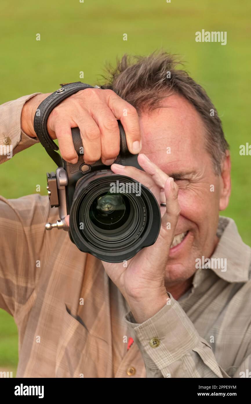 Nahaufnahme eines Fotografen mit Kamera in Aufnahmeposition, Kamera vor, grüner Hintergrund, Pantanal Wetlands, Mato Grosso, Brasilien Stockfoto