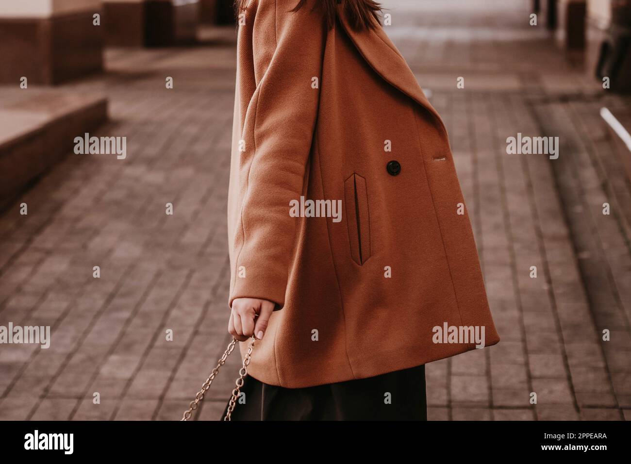 Junge Frau mit verkürztem Kopf in gestricktem langem braunen Mantel. Lässiger Street-Style im Herbst Stockfoto