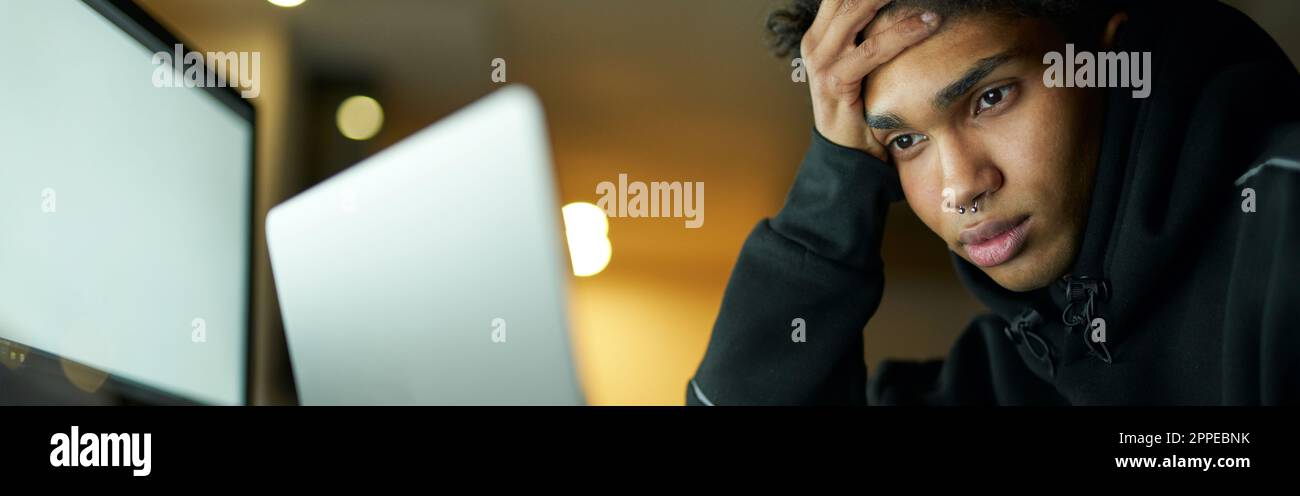 Müde junge Kerl studieren oder arbeiten auf Laptop, sitzen in dunklen Raum zu Hause spät in der Nacht Stockfoto