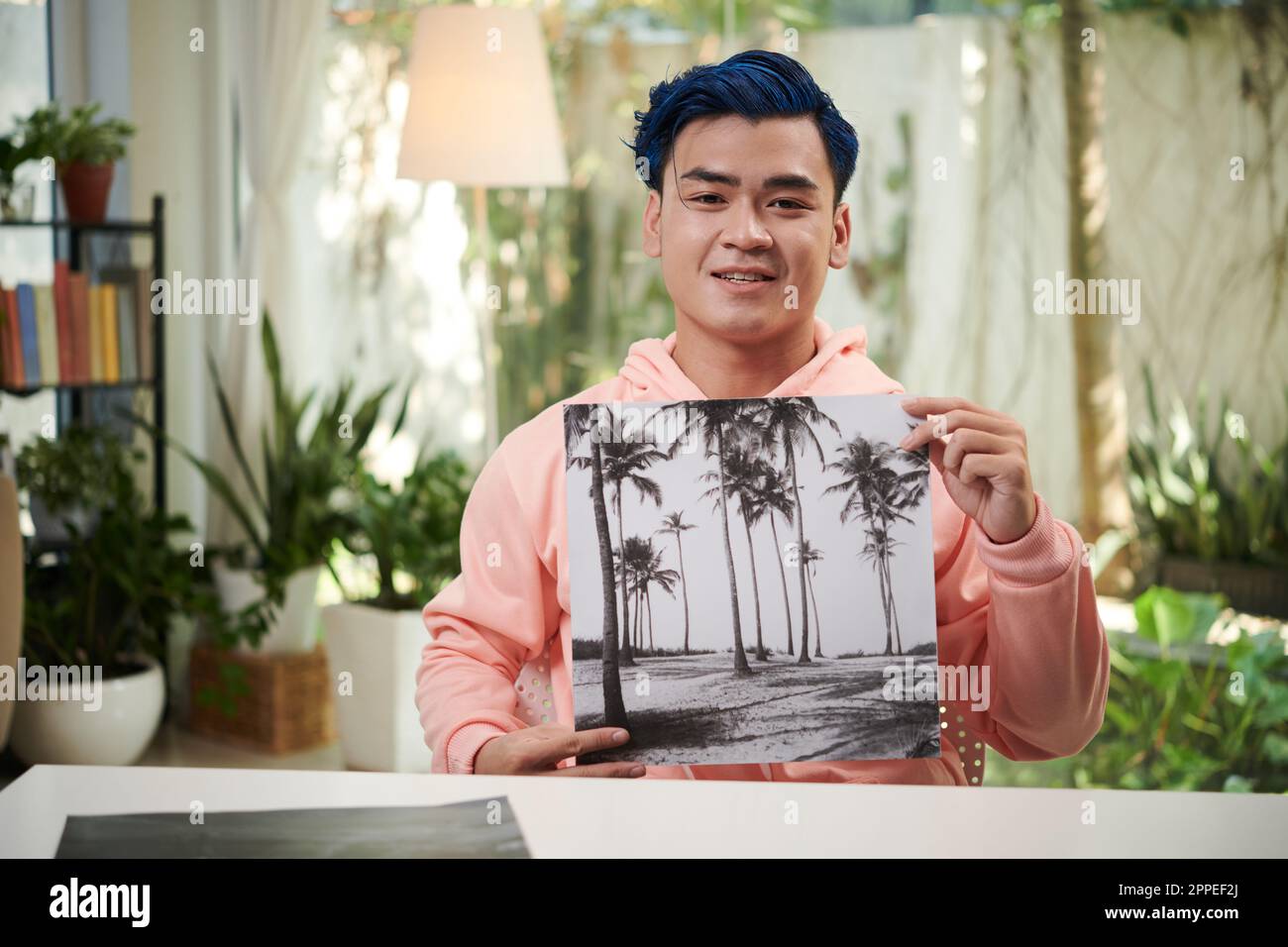 Glücklicher kreativer junger Mann, der ein Schwarz-Weiß-Foto zeigt, das er für seine persönliche Ausstellung gemacht hat Stockfoto