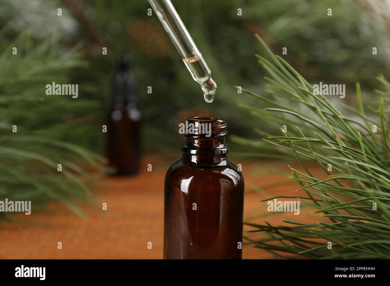 Ätherisches Kiefernöl in die Flasche am Holztisch tropfen lassen, schließen Stockfoto