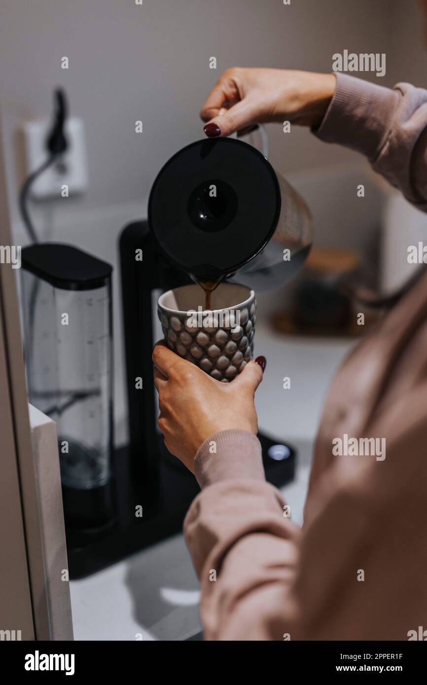 Frauenhände schütten Kaffee in eine Tasse Stockfoto