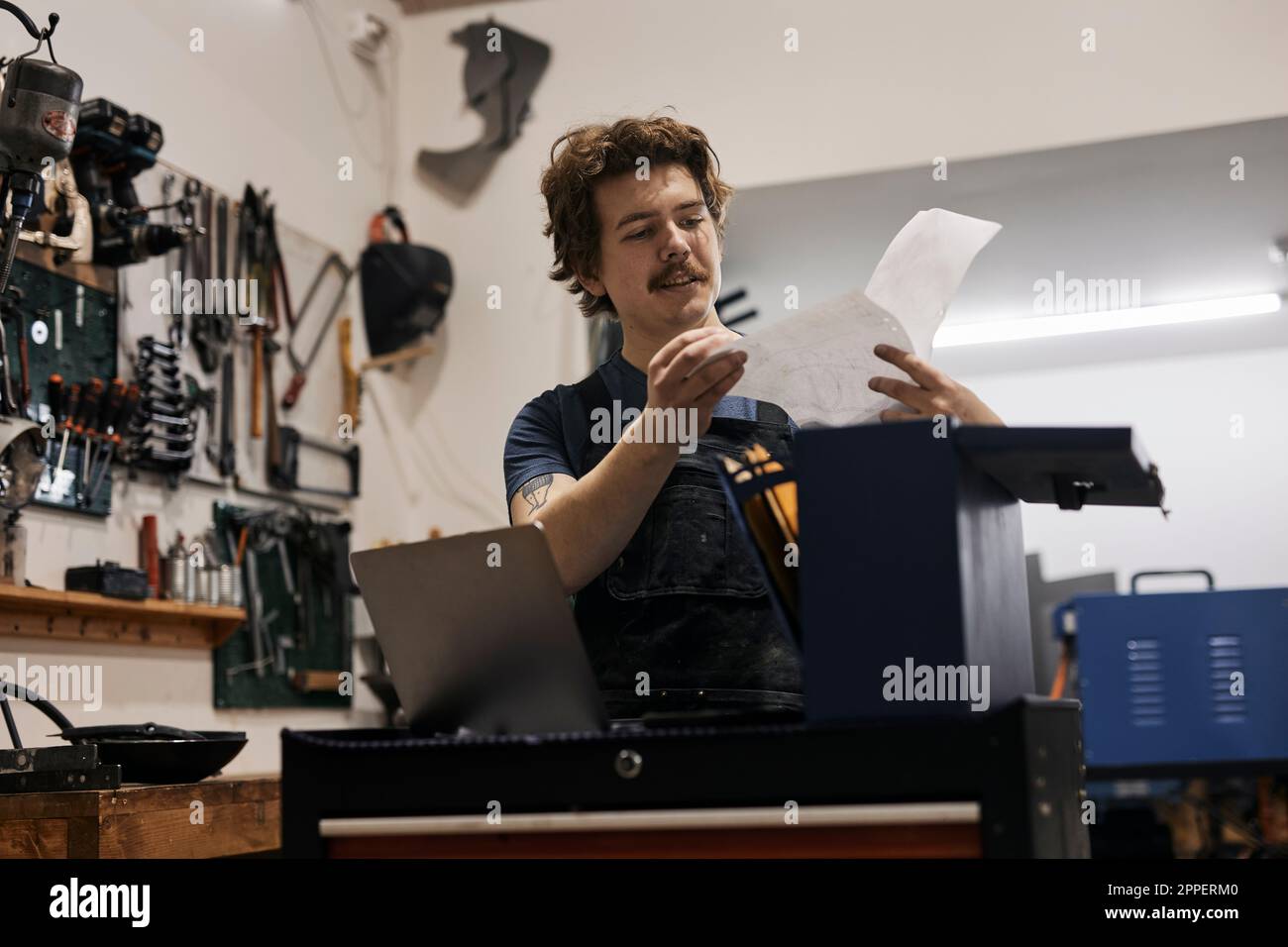 Hufschmied liest Dokumente in seiner Werkstatt Stockfoto