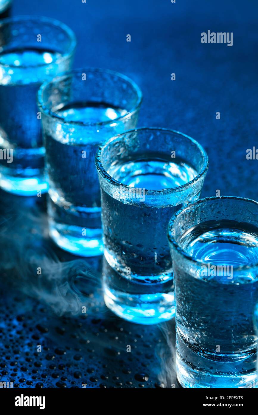 Nasse Gläser Wodka in Rauch auf dunkelblauem Hintergrund. Selektiver Fokus. Stockfoto