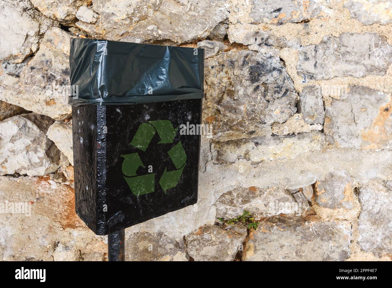 Schwarzer Mülleimer mit grünem Recycling-Symbol auf der Straße, einschließlich Kopierfeld Stockfoto