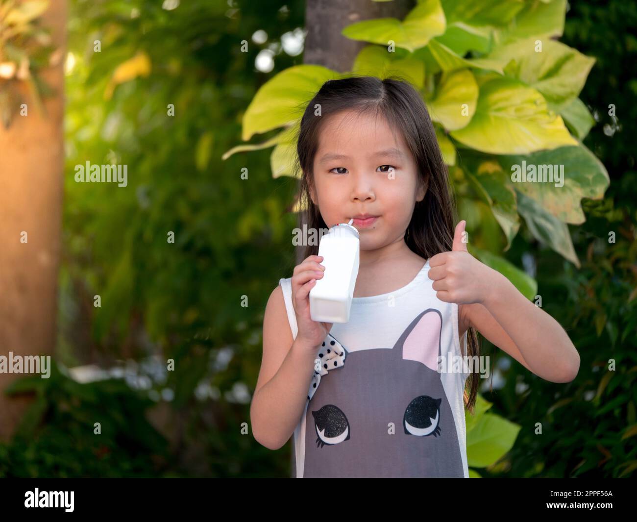 Portrait eines süßen, asiatischen Mädchens, das eine Flasche Milch hält Stockfoto