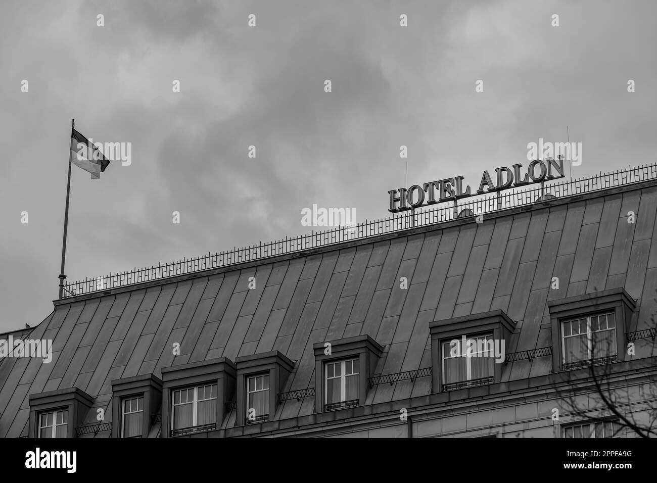 Berlin, Deutschland - 18. April 2023 : Blick auf das berühmte Adlon Hotel und die deutsche Nationalflagge in Berlin in Schwarz und Weiß Stockfoto