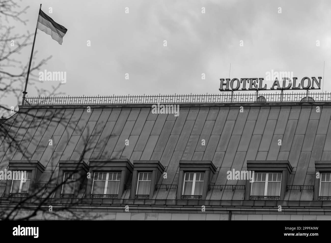 Berlin, Deutschland - 18. April 2023 : Blick auf das berühmte Adlon Hotel und die deutsche Nationalflagge in Berlin in Schwarz und Weiß Stockfoto
