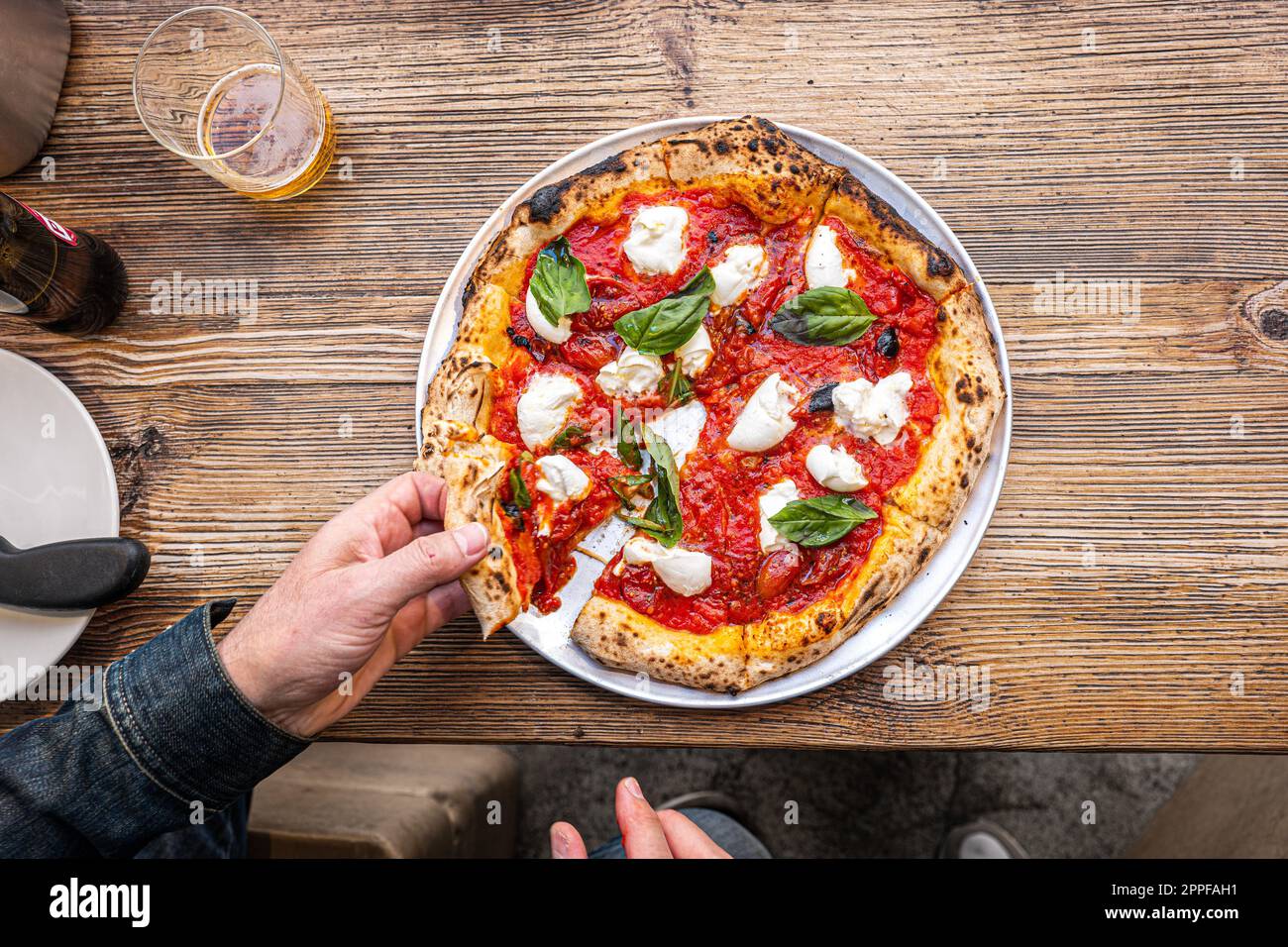 Neapolitanische Margherita Pizza auf einem rustikalen Holztisch in einer traditionellen Pizzeria. Stockfoto
