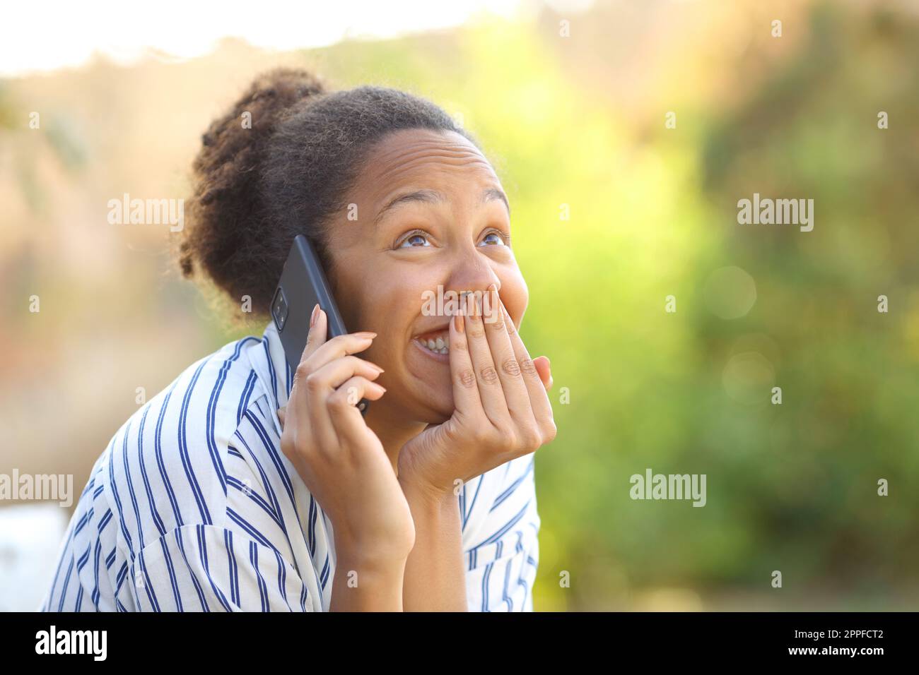 Komische schwarze Frau, die in einem Park telefoniert Stockfoto