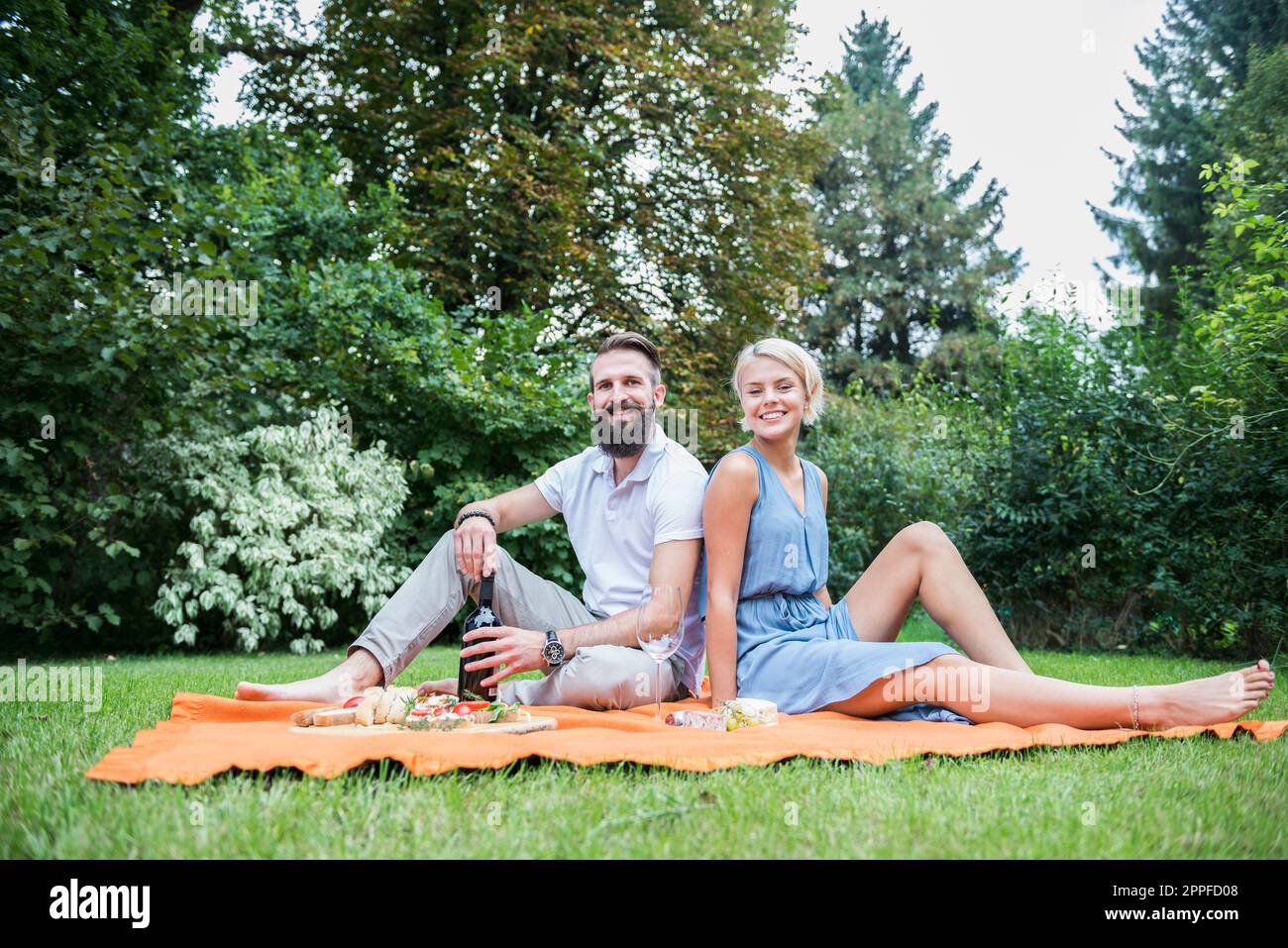 Ein junges Paar genießt ein Picknick im Garten in Bayern Stockfoto