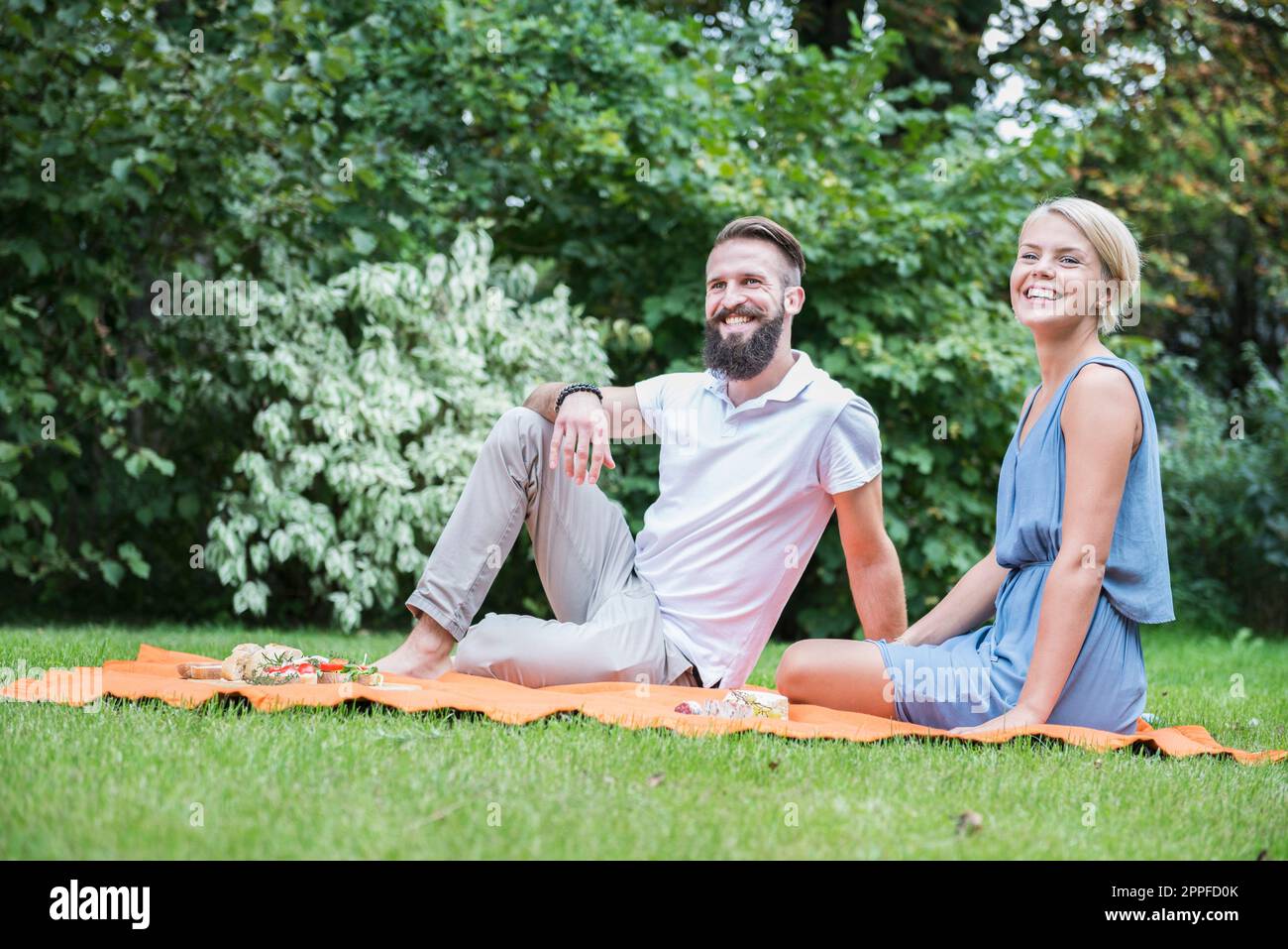 Ein junges Paar genießt ein Picknick im Garten in Bayern Stockfoto