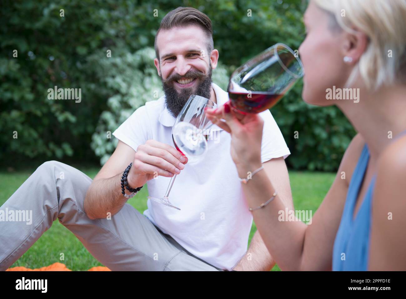 Ein junges Paar genießt Rotwein beim Picknick in Bayern Stockfoto