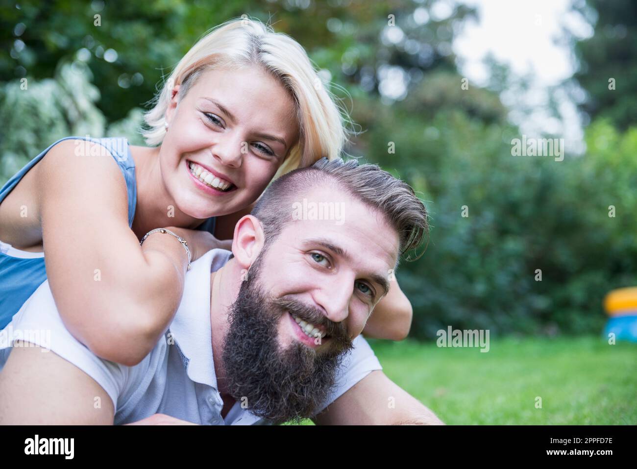 Porträt eines glücklichen jungen Paares, das im Garten liegt, Bayern, Deutschland Stockfoto