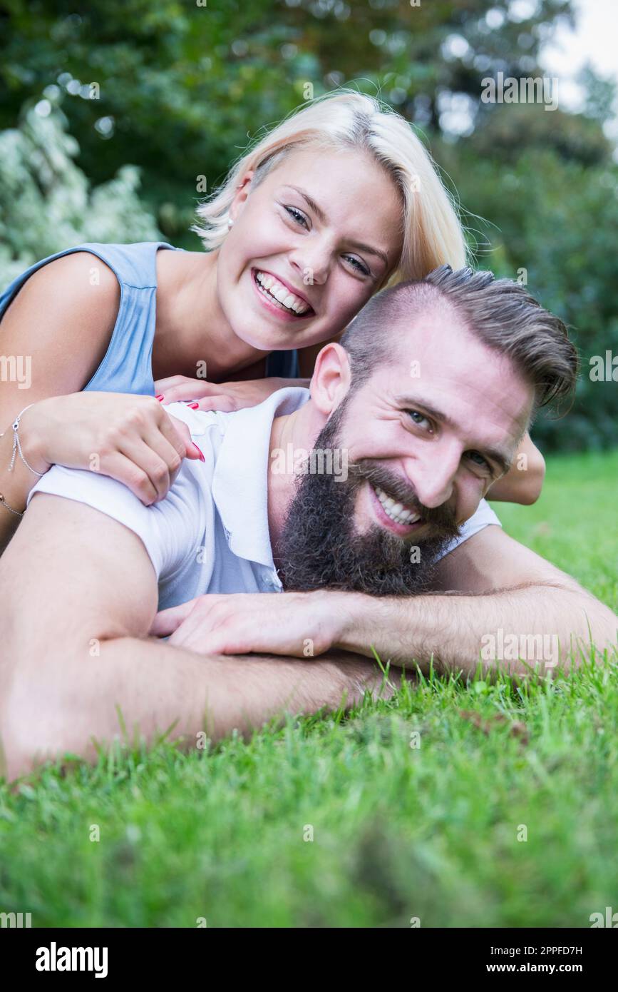 Porträt eines glücklichen jungen Paares, das im Garten liegt, Bayern, Deutschland Stockfoto