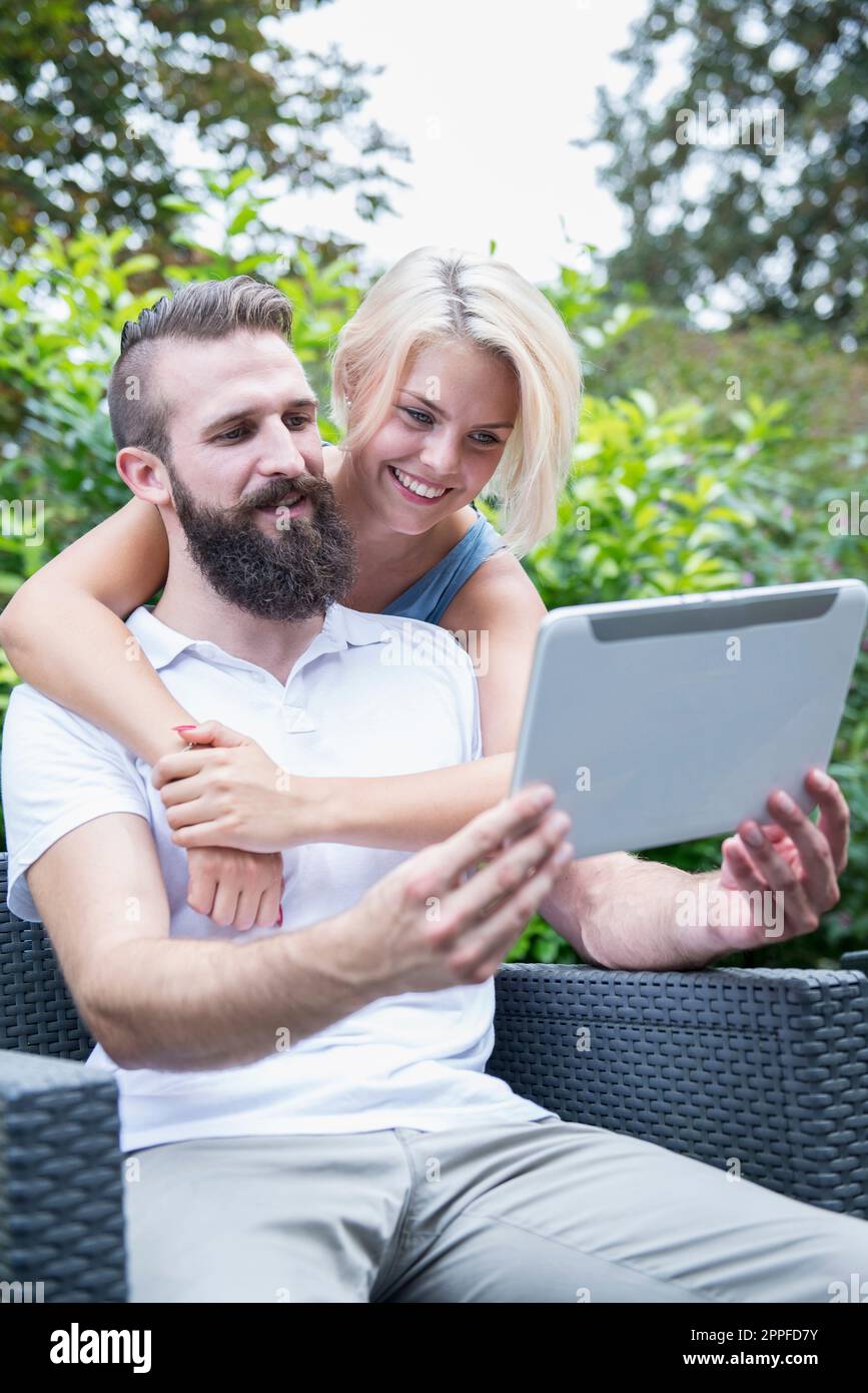 Glückliches junges Paar, das ein Selfie mit einem digitalen Tablet im Garten in Bayern macht Stockfoto
