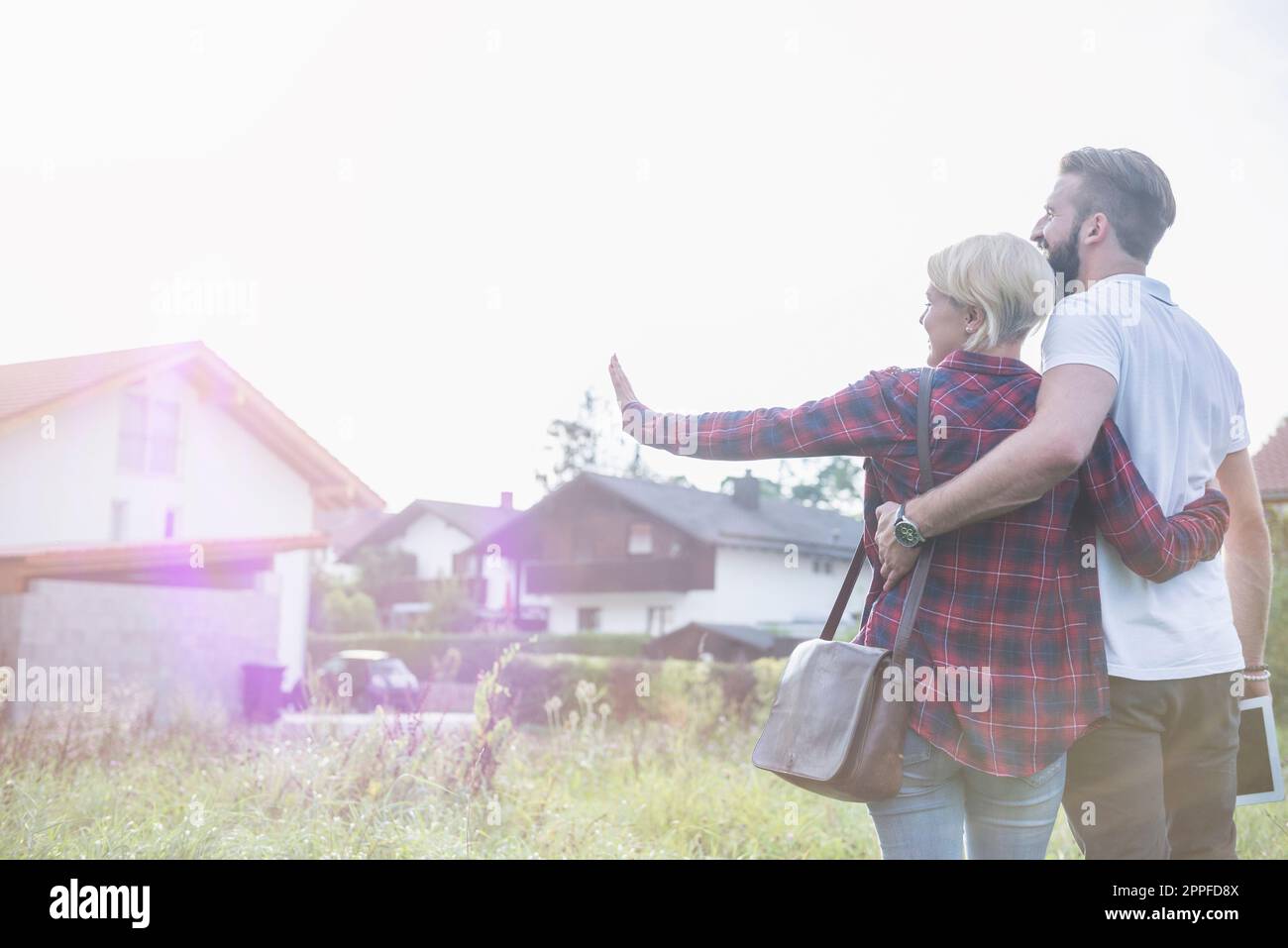 Ein junges Paar umarmt sich und stellt sich ihr zukünftiges Haus vor, Bayern, Deutschland Stockfoto