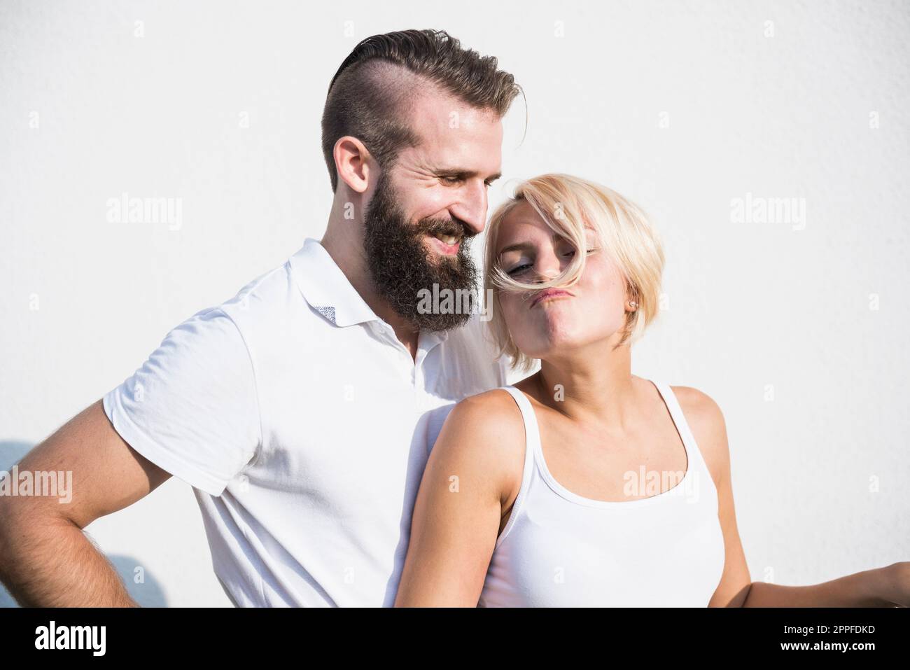 Ein junger Mann, der mit seiner verspielten Freundin lächelt und Schnurrbart mit Haaren macht, Bayern, Deutschland Stockfoto