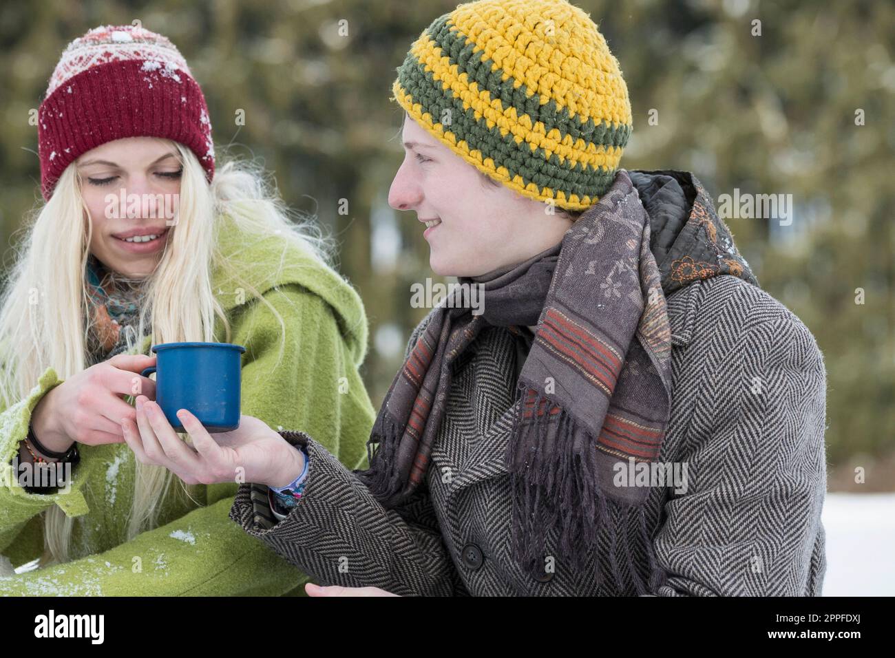 Junges Paar mit Kaffeetasse in verschneiter Landschaft im Winter, Bayern, Deutschland Stockfoto