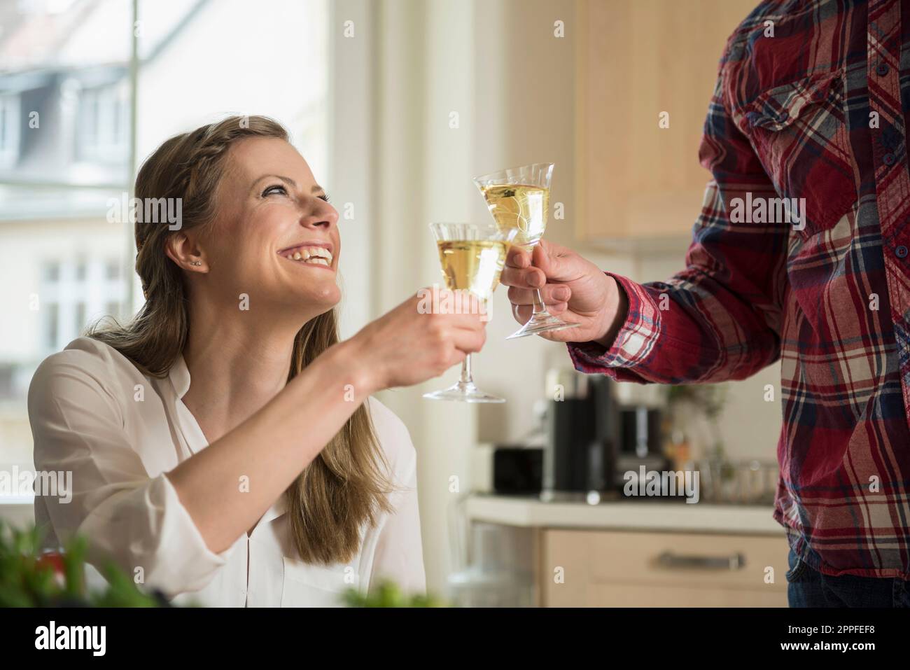 Ein Paar feiert mit Weißwein in der Küche, München, Bayern, Deutschland Stockfoto