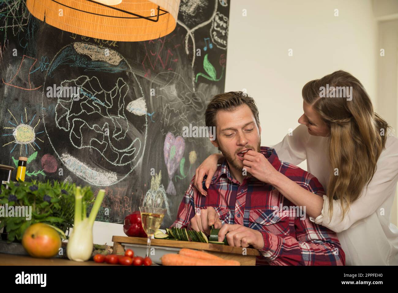 Junge Frau füttert ihren Mann in der Küche, München, Bayern, Deutschland Stockfoto