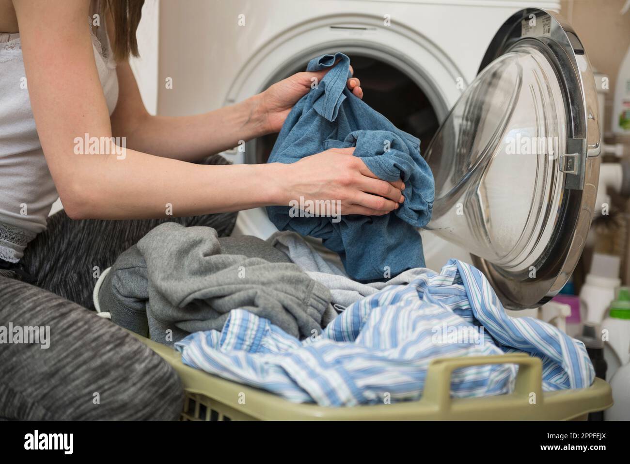 Junge Frau, die Wäsche aus der Waschmaschine holt, München, Bayern, Deutschland Stockfoto