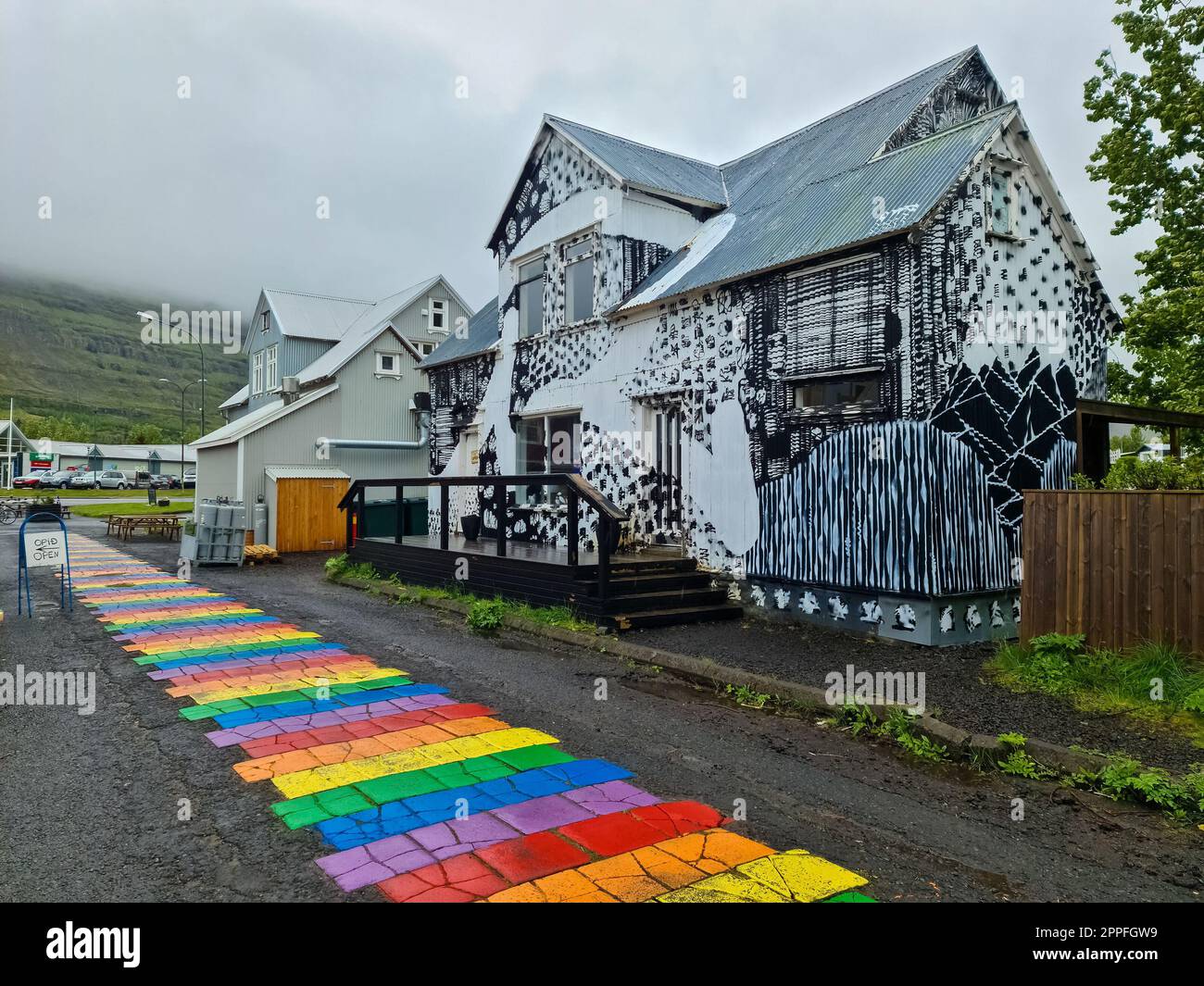 Seydisfjordur, Island - 23. Juni 2022: Die berühmte Regenbogenstraße in Seydisfjordur mit isländischen Gebäuden um bemalte Wände. Stockfoto
