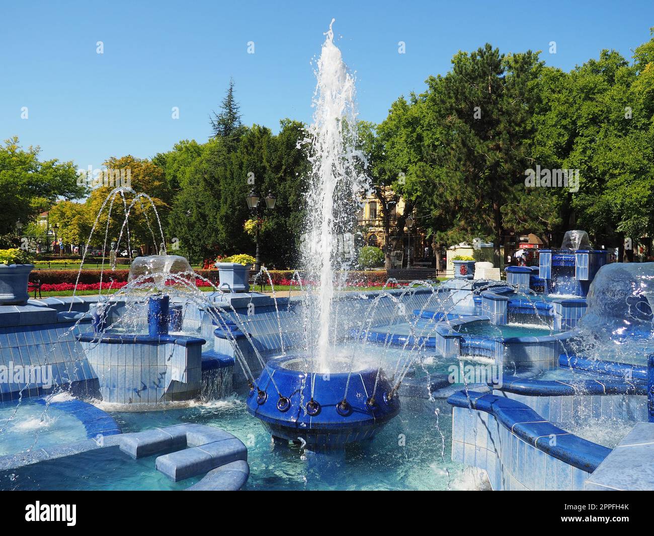 Subotica, Serbien 12. September 2021. Blauer Brunnen auf dem Platz neben dem Rathaus. Blaue Keramikteile mit Monogrammen. Ein funktionierender Brunnen mit Spritzwasser. Sommersonnentag am blauen Wasser Stockfoto