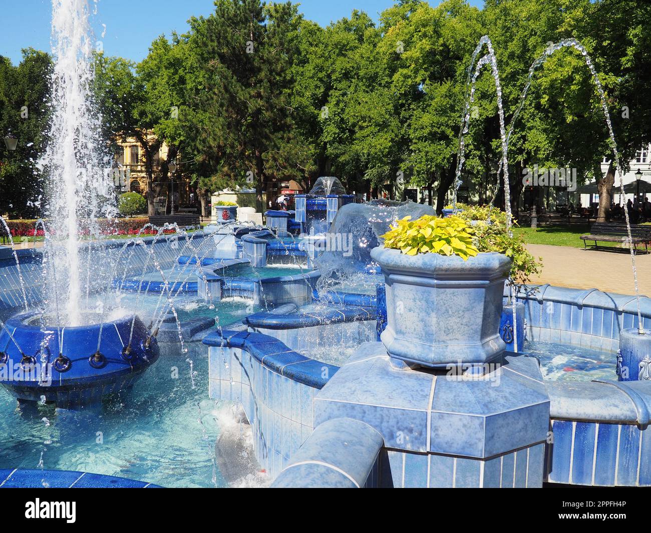 Subotica, Serbien 12. September 2021. Blauer Brunnen auf dem Platz neben dem Rathaus. Blaue Keramikteile mit Monogrammen. Ein funktionierender Brunnen mit Spritzwasser. Sommersonnentag am blauen Wasser Stockfoto