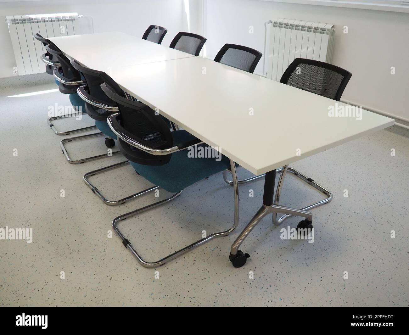 Tisch und Stühle im Tagungsraum oder im Auditorium. Bibliothek, Büro oder Räumlichkeiten in einer offiziellen Einrichtung oder Bank. Es ist niemand am Tisch. Weiße, schwarze und graue Farben im Innenraum Stockfoto