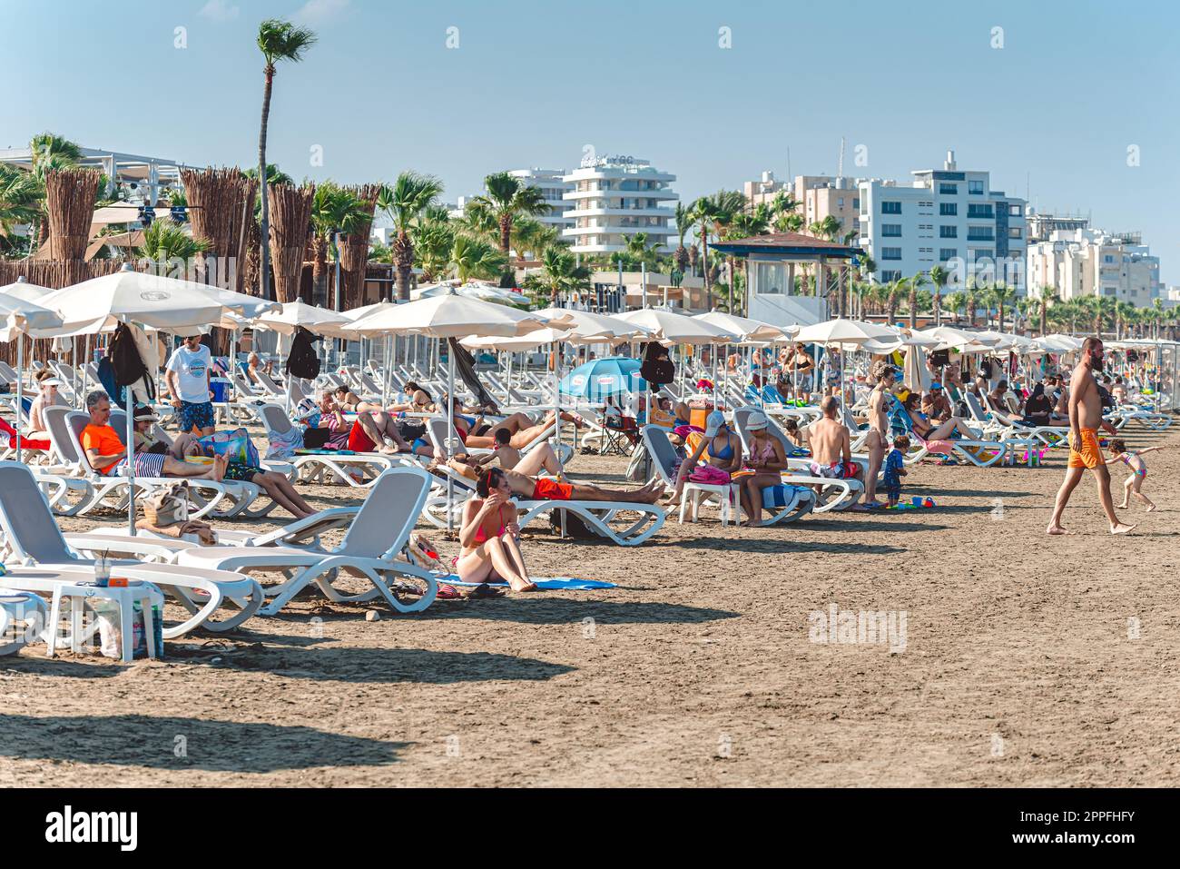 Larnaca, Zypern - 09. Juli 2022: Touristen, die sich am Mackenzie Strand sonnen Stockfoto