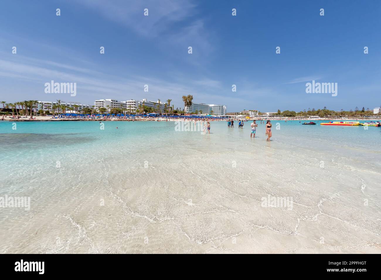 Ayia Napa, Zypern - 07. April 2018: Touristen, die am Strand von Nissi spazieren und baden Stockfoto