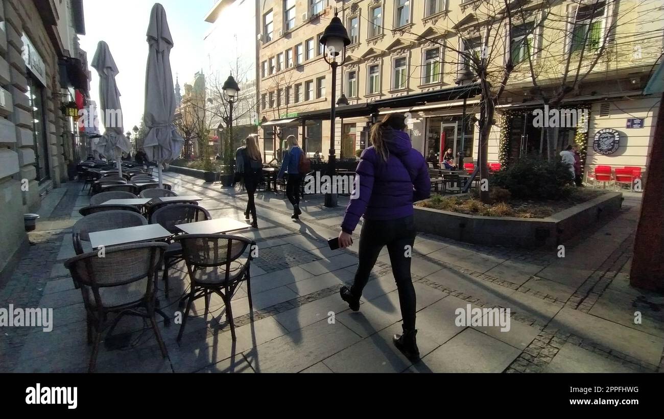 Belgrad, Serbien - 24. Januar 2020: Morgenstraße im Stadtzentrum. Die Leute hetzen sich um ihre Geschäfte. Straßencafés sind immer noch geschlossen. Tische, Stühle und Sonnenschirme. Mädchen gehen energisch Stockfoto