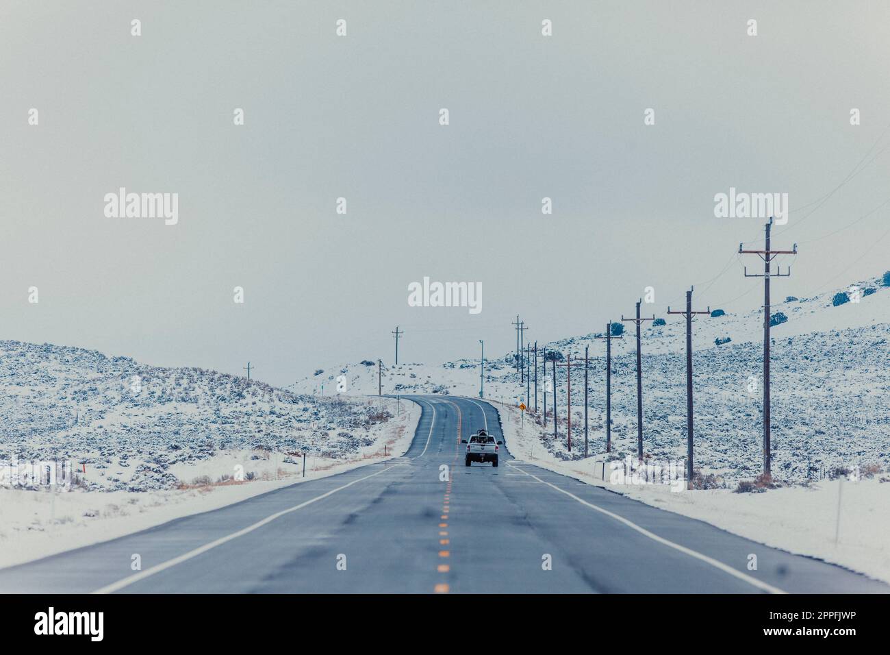 Ein Lkw fährt im Winter eine lange Straße entlang. Stockfoto