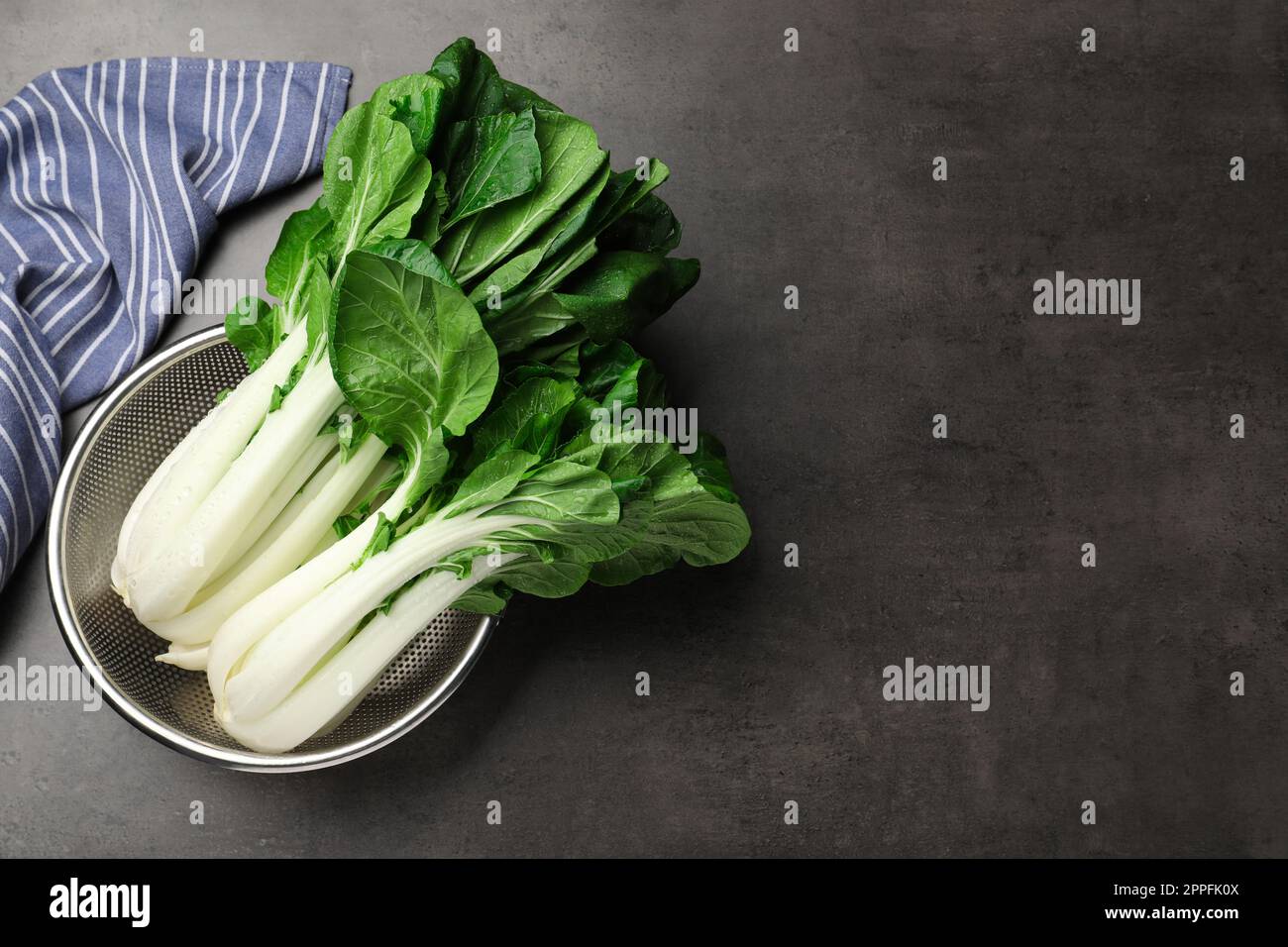 Frischer grüner pak Choy Kohl mit Wassertropfen im Sieb auf grauem Tisch, Draufsicht. Platz für Text Stockfoto