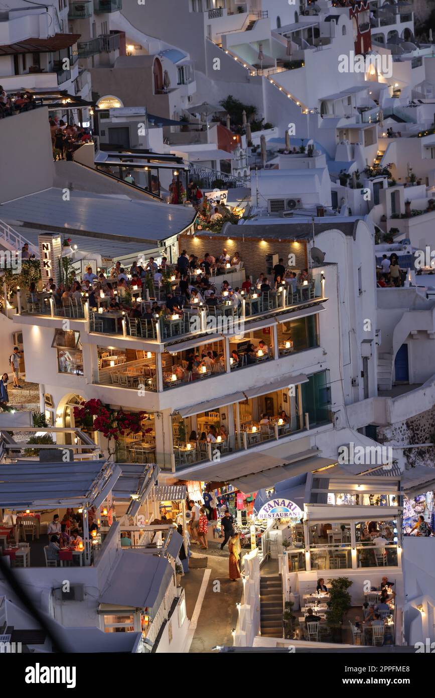 Beleuchtete Balkonterrassen und Terrassen mit Restaurants der Stadt Fira auf Santorini Insel. Stockfoto