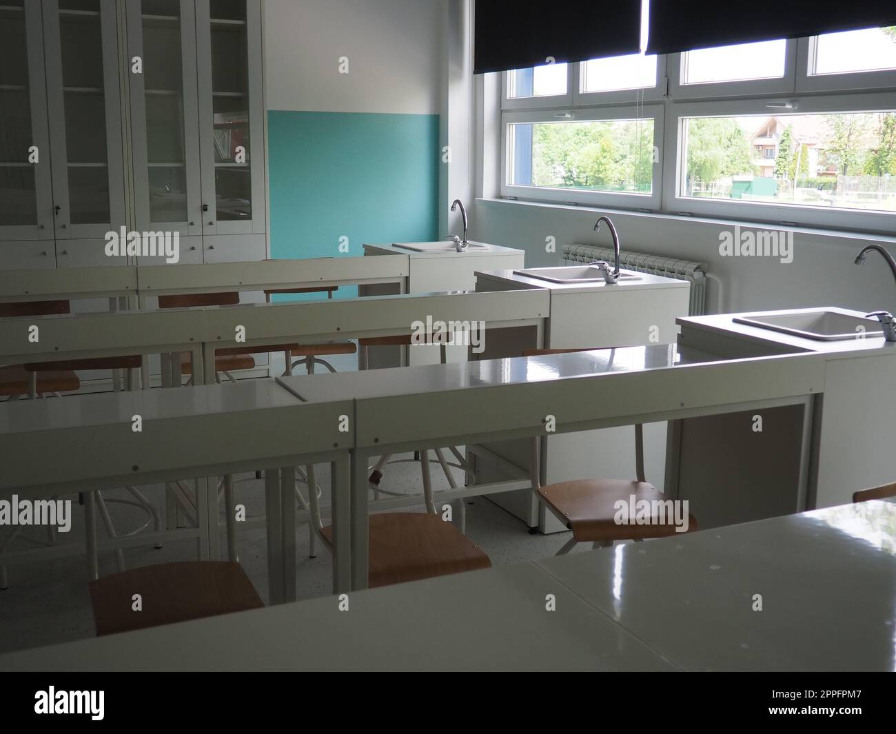 Chemiezimmer in einer modernen neuen Schule. Wunderschöne weiße Möbel mit Waschbecken und Waschbecken. Große Fenster mit Verdunkelungsvorhängen oder Jalousien. Leeres Klassenzimmer. Möbel und Schulausstattung Stockfoto
