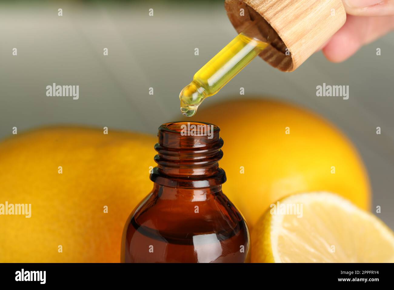 Frau tropft ätherisches Öl in Flasche und Zitronen, Nahaufnahme Stockfoto