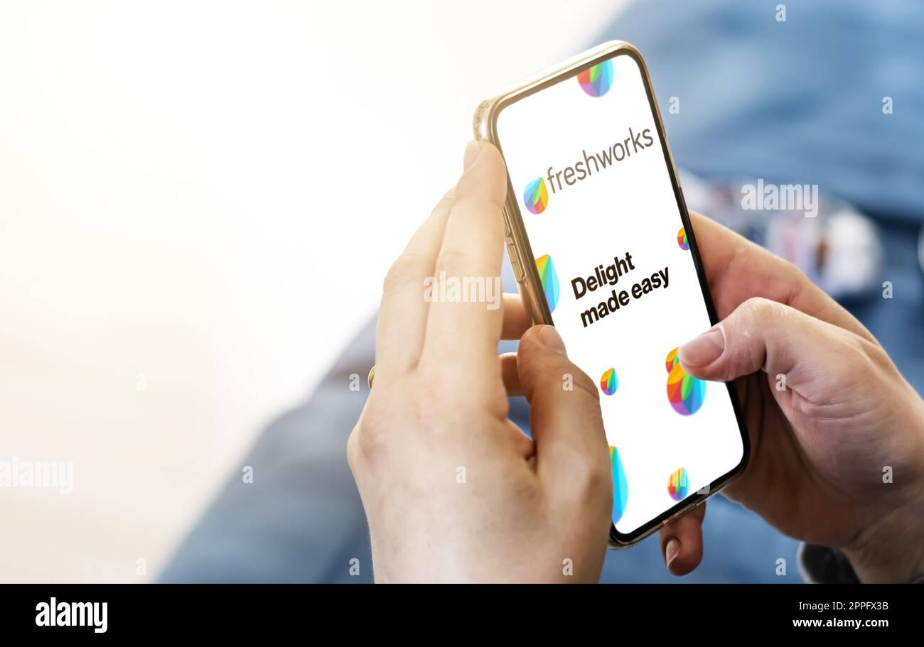Weibliche Hände halten ein Telefon mit Freshworks-Webseite auf dem Bildschirm Stockfoto