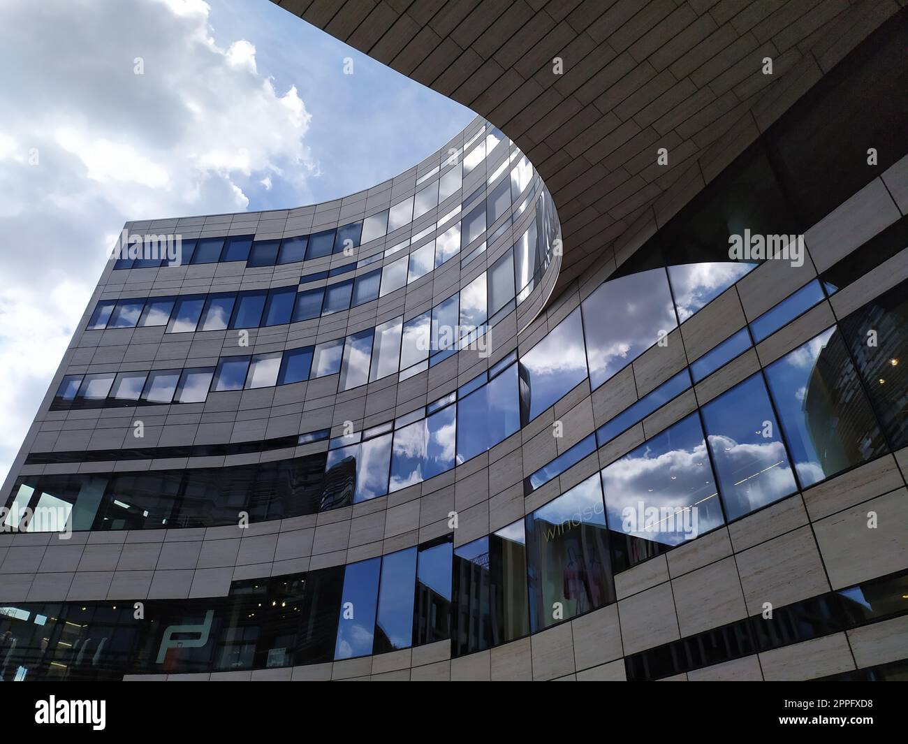 Düsseldorf, Deutschland - 16. Juli 2022: Moderne Architektur des DÃ¼sseldorfer KÃ¶bogen im Sommer zeigt eine attraktive und extravagante Glasfassade aus biologischem und geschwungenem Einkaufszentrum mit blauen Wolken Stockfoto