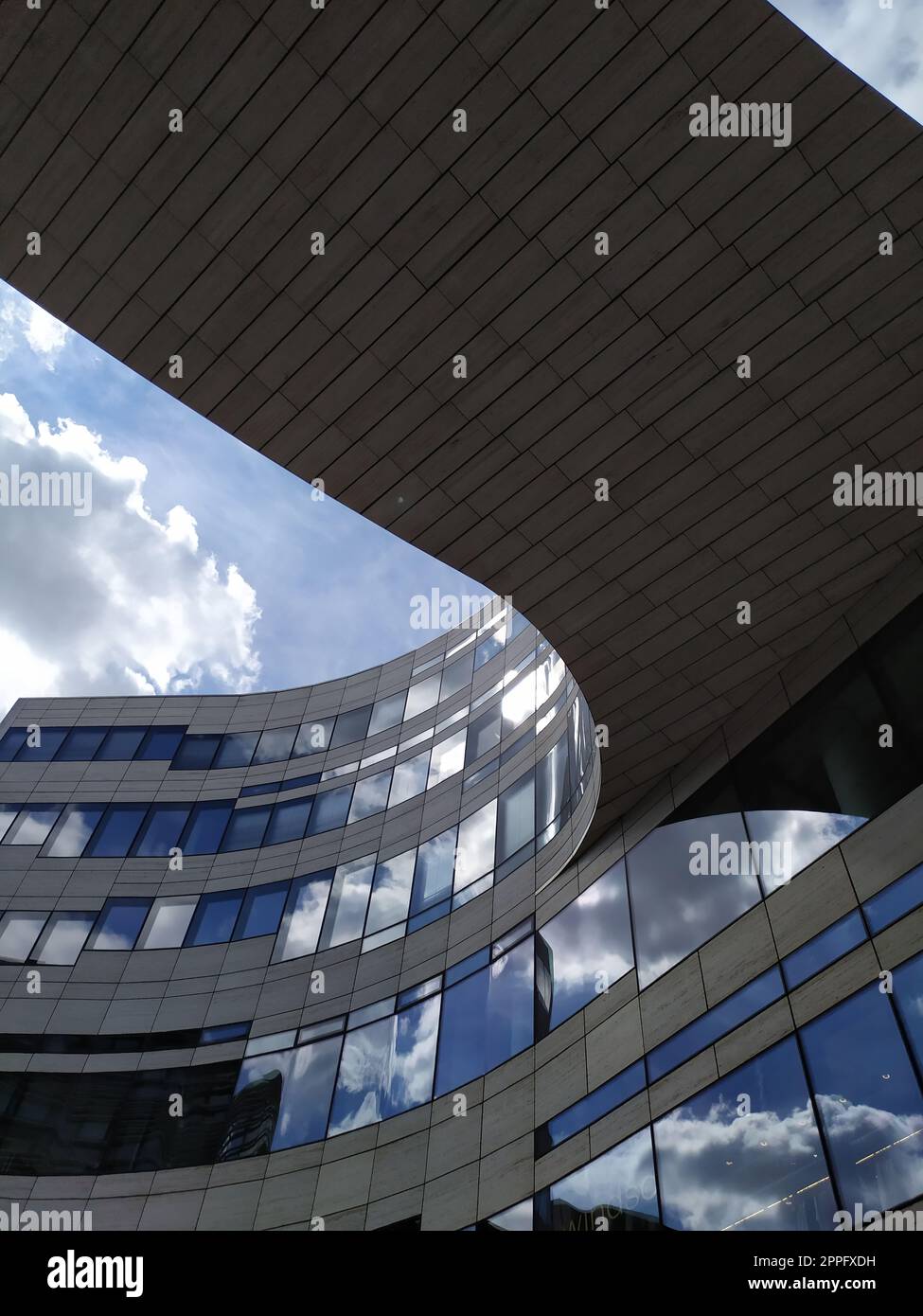 Düsseldorf, Deutschland - 16. Juli 2022: Moderne Architektur des DÃ¼sseldorfer KÃ¶bogen im Sommer zeigt eine attraktive und extravagante Glasfassade aus biologischem und geschwungenem Einkaufszentrum mit blauen Wolken Stockfoto